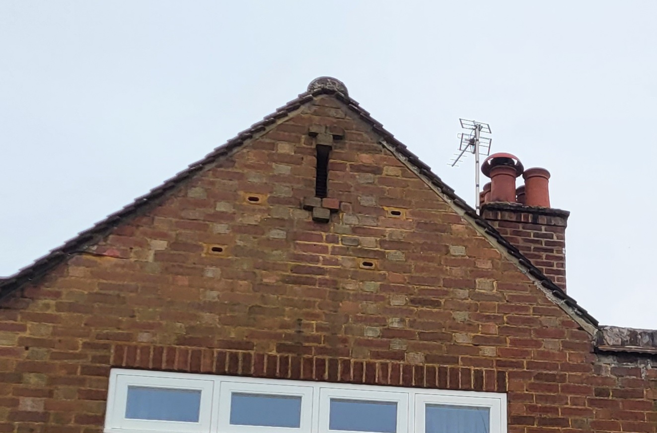 The gable end of the house showing entrance holes drilled into the brickwork